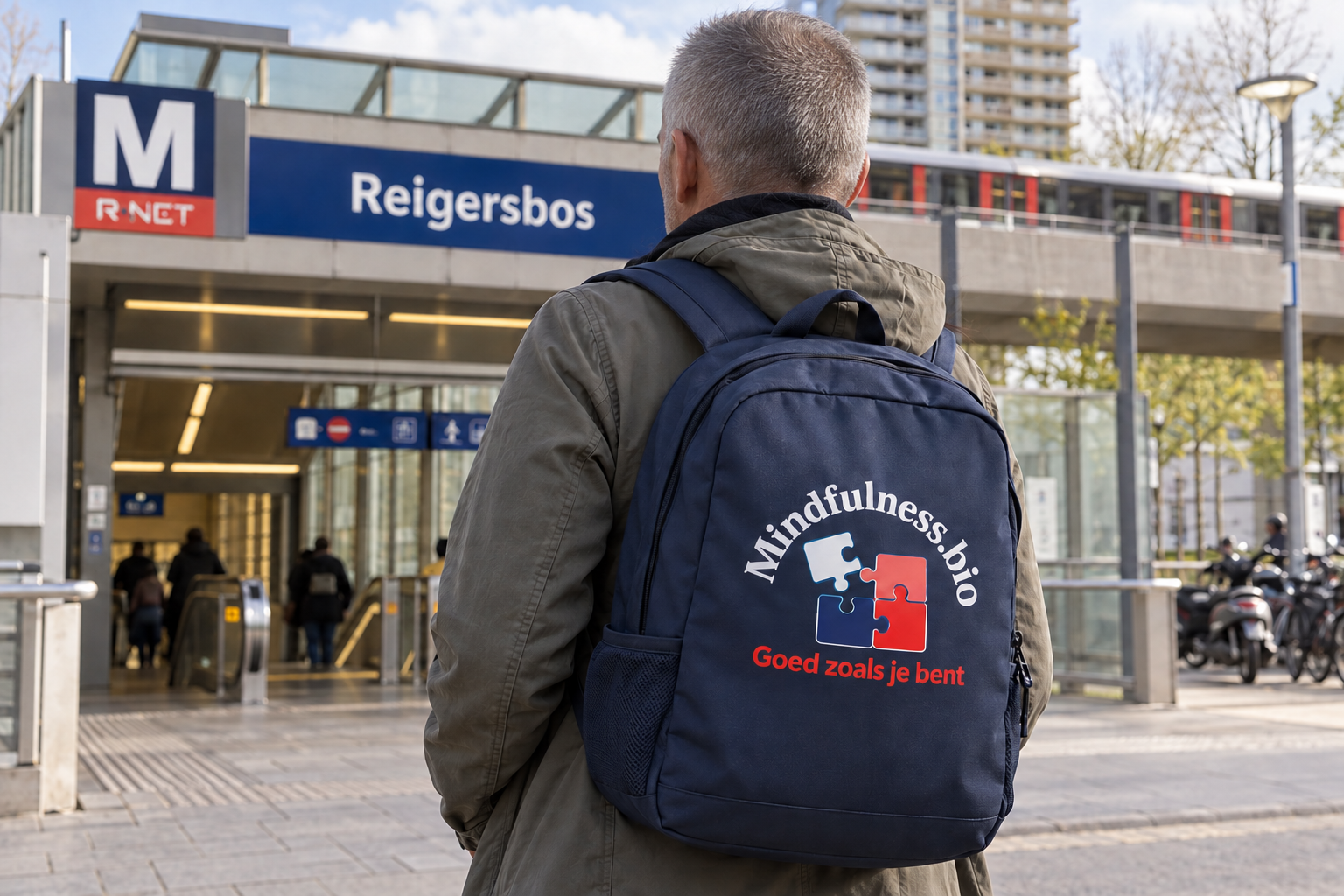 Grijsharige man met een Mindfulness Bio-rugzak bij metro Reigersbos